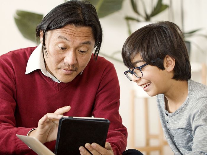 A father and his son look at a tablet together
